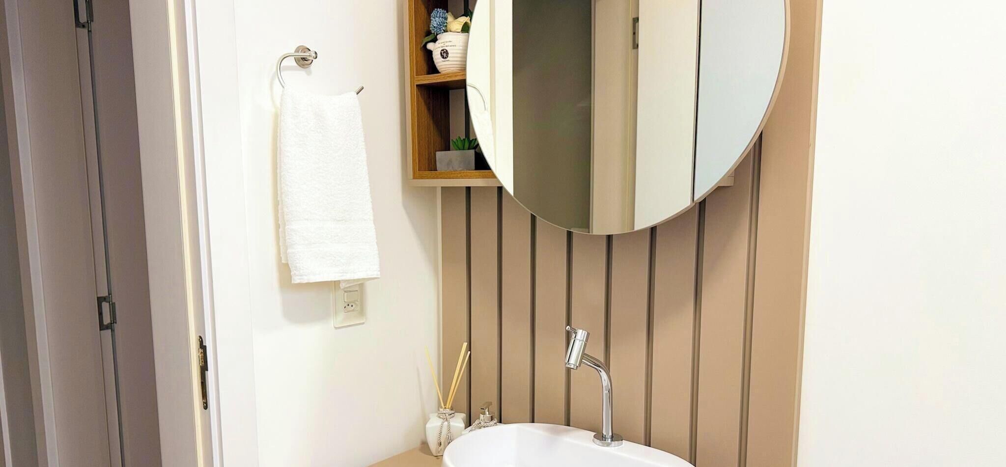 A bathroom with a white sink, a mirror, and a towel hanging on a rack.