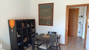 Un coin repas avec une table et des chaises, une bibliothèque et un tableau accroché au mur.