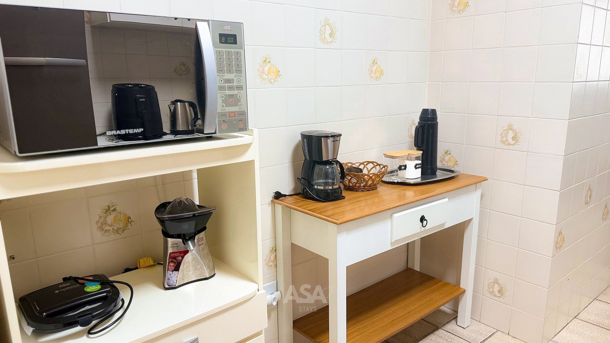 A kitchenette with a microwave, coffee maker, and coffee pot on a white cabinet.