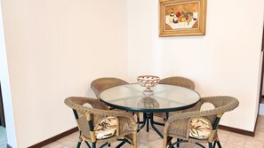 A round table with six wicker chairs, a glass top, and a decorative bowl. - ASA Apto Central 2 QT Climatizado BC (Balneário Camboriú)