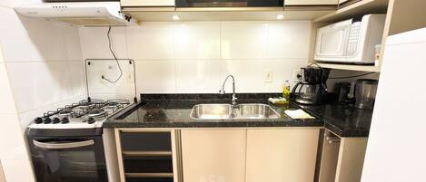 A compact kitchen with a gas stove, a built-in oven, a sink, and a microwave.