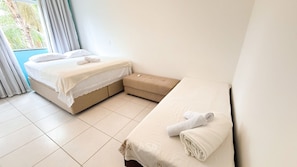 A hotel room with two beds, a small sofa, and a window with curtains. - ASA Apto Confortavel Indaial 2 QT Garagem (Indaial)