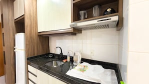 Una cocina con encimera negra, pileta de acero inoxidable, cafetera y hervidor.
