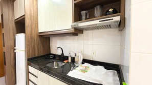 A kitchen with a black countertop, a stainless steel sink, a coffee maker, and a kettle. - ASA Indaial Apartment Vale Europeu Gated Community (Indaial)