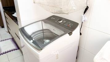 A front-loading washing machine with a control panel, a power cord, and a protective mesh cover.