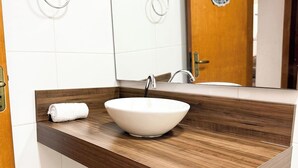 Un baño con tocador de madera, un lavabo blanco y una toalla.