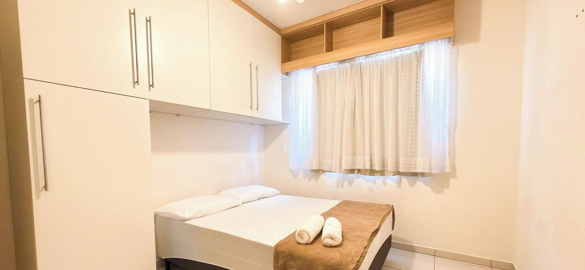 Ein Schlafzimmer mit Bett, einem Fenster mit Vorhängen und Einbauschränken.