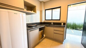 A compact kitchen with a built-in refrigerator, a window above the sink, and a countertop with a kettle. - ASA Smart Living Studio Downtown Balneario Camboriu (Balneário Camboriú)