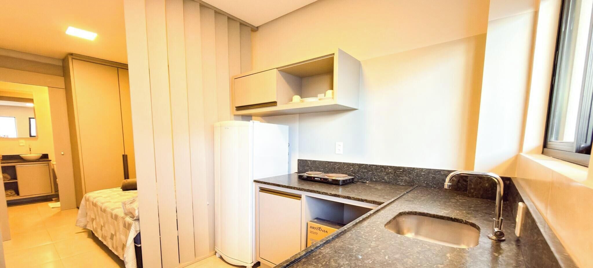 A compact kitchen with a refrigerator, a sink, and a countertop.