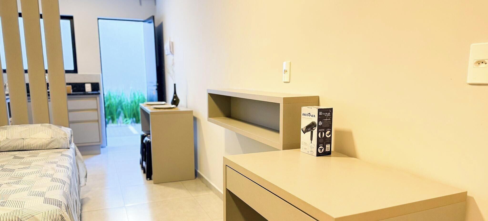 Ett modernt hotellrum med en säng, ett skrivbord och en stol. Det finns ett fönster med utsikt över grönområden utanför.