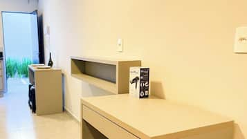 Ett modernt hotellrum med en säng, ett skrivbord och en stol. Det finns ett fönster med utsikt över grönområden utanför.