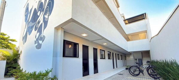 A modern building with a covered walkway, black doors, and a bicycle parked outside. - ASA Smart Living Studio Downtown Balneario Camboriu (Balneário Camboriú)