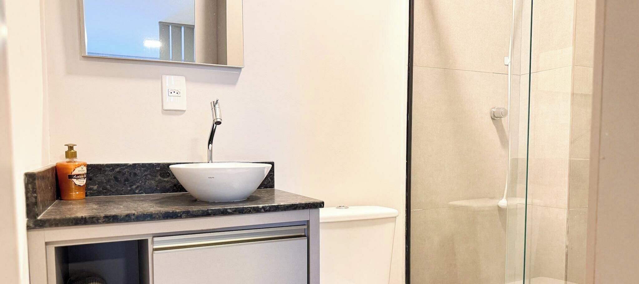A bathroom with a white sink, a mirror above it, and a shower area.