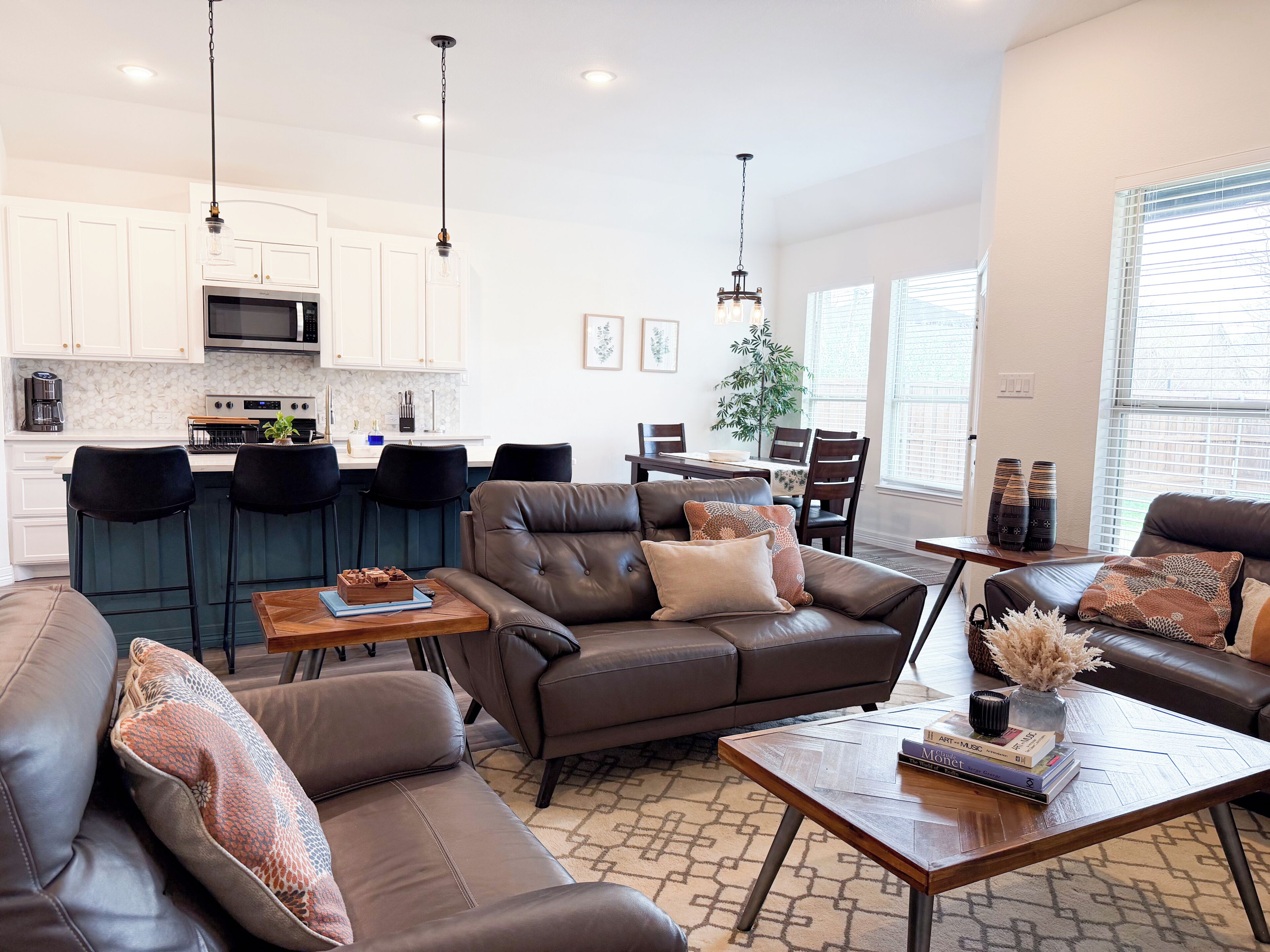 A modern living room with leather sofas, a coffee table, and a dining area with chairs and a table.