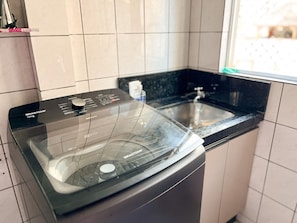 Eine Waschmaschine mit Frontlader, ein Edelstahl-Spülbecken und ein Fenster in einer Küche.