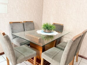 A glass-top dining table with six grey upholstered chairs, a central potted plant, and a white doily on the table. - ASA Apto Funcional Prox. Praia Centro BC (Balneário Camboriú)