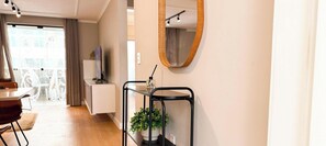 Ein modernes Wohnzimmer mit Essbereich, einem kleinen Tisch mit Pflanze und einem Spiegel an der Wand.