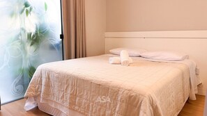 A neatly made bed with a quilted bedspread, a rolled towel, and two pillows. - ASA 3QT Reno Suite Ar Cond. Centro BC (Balneário Camboriú)
