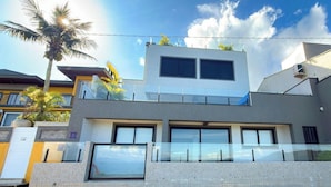 A modern two-story building with large windows and a balcony. - ASA Beachfront 5 Suites Jacuzzi Bombinhas (Bombinhas)