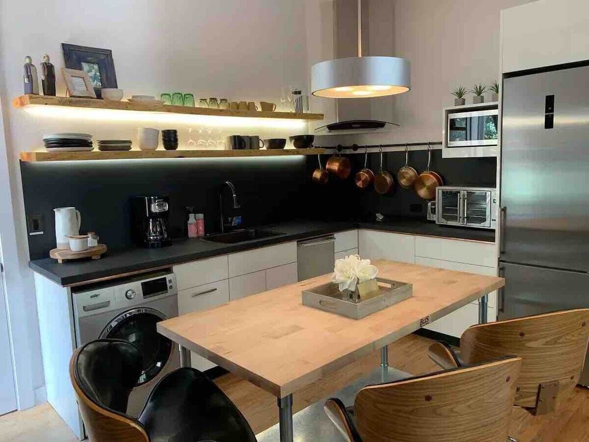 A modern kitchen with a central island, stainless steel appliances, and a pendant light.