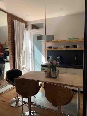 Een moderne keuken met een eethoek, inclusief een tafel met twee stoelen, een vaas met bloemen en een hanglamp.