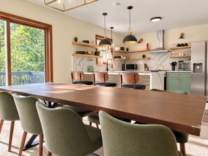 A modern kitchen with a dining area, featuring a large wooden table, green upholstered chairs, and pendant lighting. - TNT Pocono Haven - 5BR - Sleeps 14 - Minutes from Kalahari (Pocono Summit)