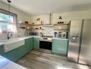 Eine moderne Küche mit türkis-farbenen Schränken, Edelstahlgeräten und Holzböden.