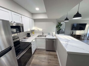 A modern kitchen with stainless steel appliances, a marble countertop, and a built-in dishwasher.