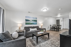 A modern living room with a sofa, coffee table, and a painting on the wall.