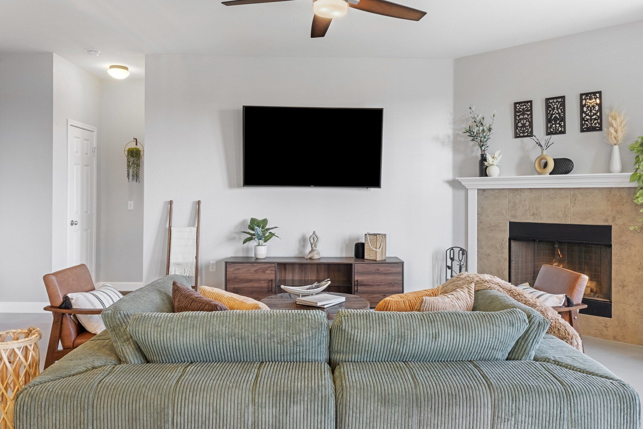 Ein modernes Wohnzimmer mit einer Couch, Sesseln, einem Flachbildfernseher, einem Kamin und Dekorationselementen.