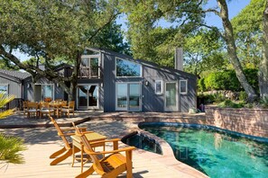 Une maison moderne à deux étages, dotée d’une piscine, d’un espace de détente extérieur et d’un jardin bien entretenu.
