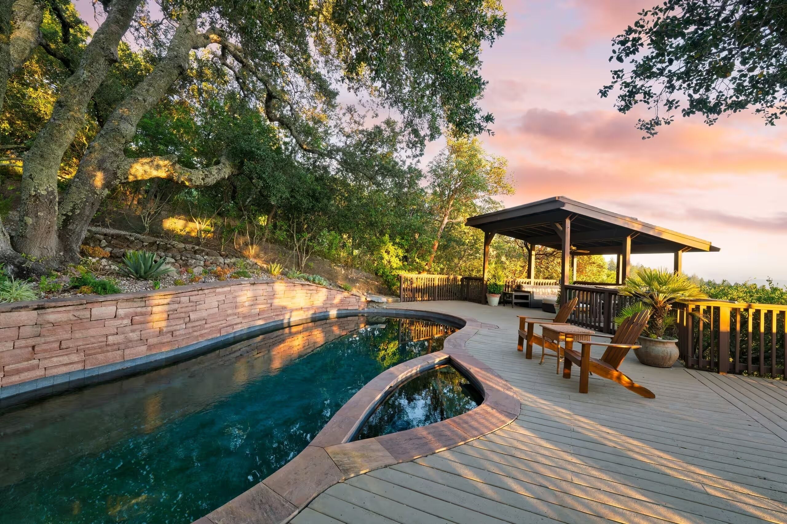 Une piscine dotée d’une terrasse en bois et d’un espace salon abrité.