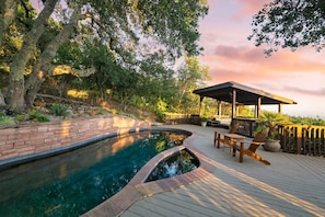 Une piscine dotée d’une terrasse en bois et d’un espace salon abrité.