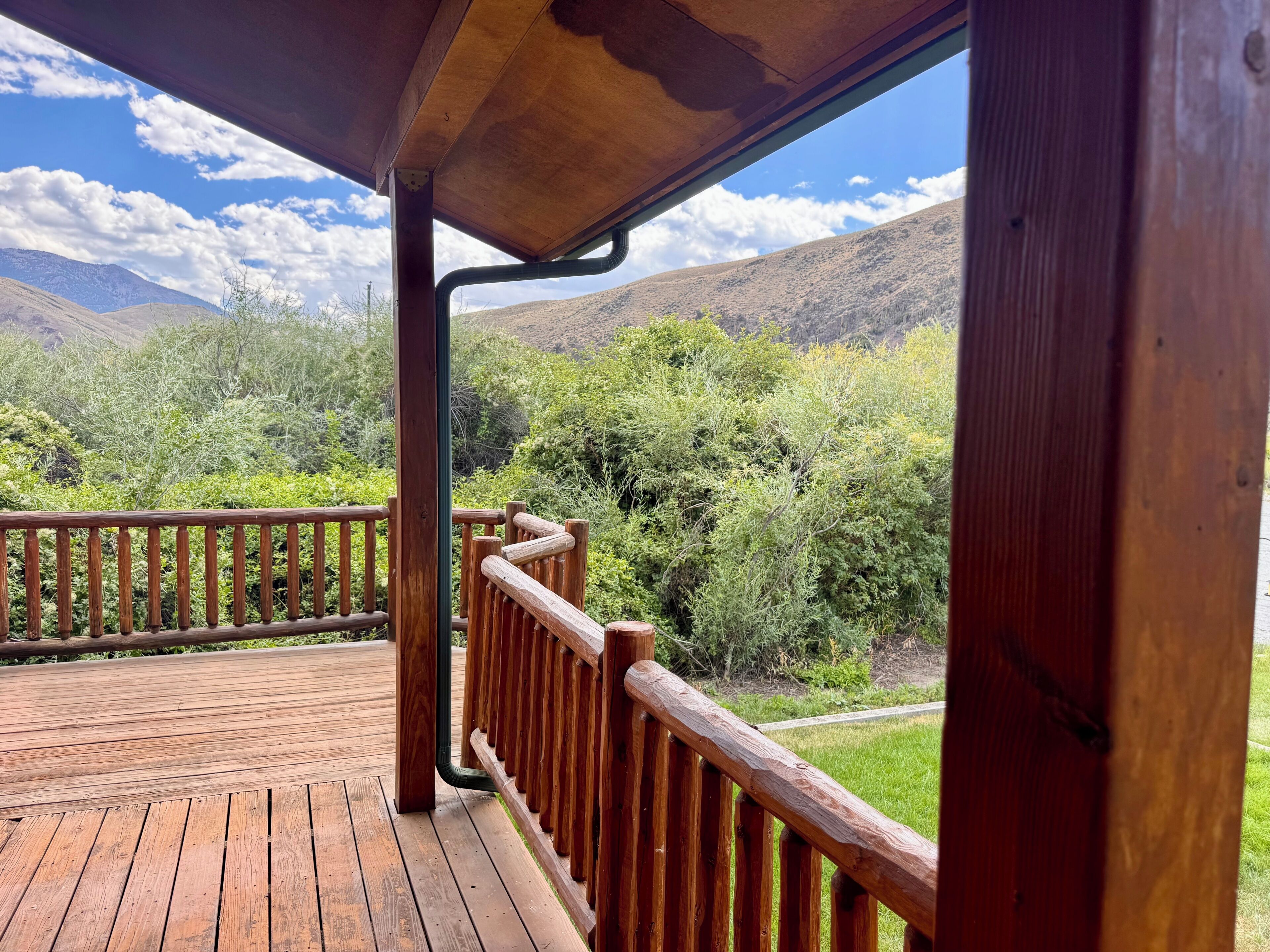 Varanda de madeira com guarda-corpo, com vista para uma paisagem montanhosa.