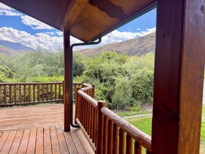 A wooden deck with a railing overlooking a mountainous landscape.