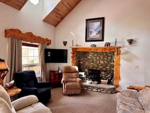 A living room with a stone fireplace, a flat-screen TV, and two sofas.