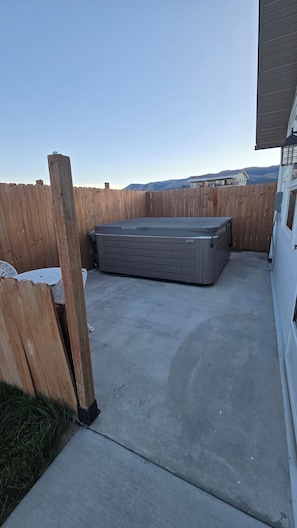 A concrete patio area with a large gray storage unit, wooden fence, and a view of distant mountains.