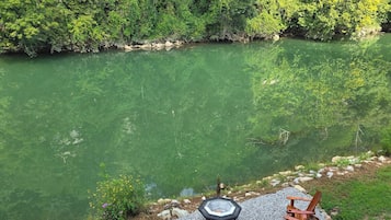 A circular outdoor seating area with a fire pit, surrounded by a gravel border, overlooking a river.