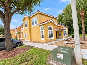 A yellow two-story house with a red-tiled roof, a driveway, and a mailbox. - 20 Min to Disney World | 4BR Pool Home (Kissimmee)