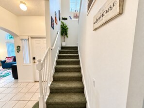 A staircase with carpeted steps and white railings leading to a door. - 20 Min to Disney World | 4BR Pool Home (Kissimmee)