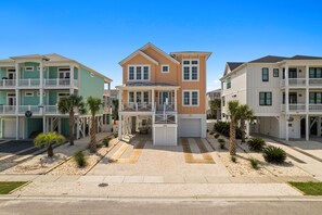 A row of beachfront condominiums with balconies, a central entrance, and a well-maintained garden. - This Must Be The Place (Ocean Isle Beach)