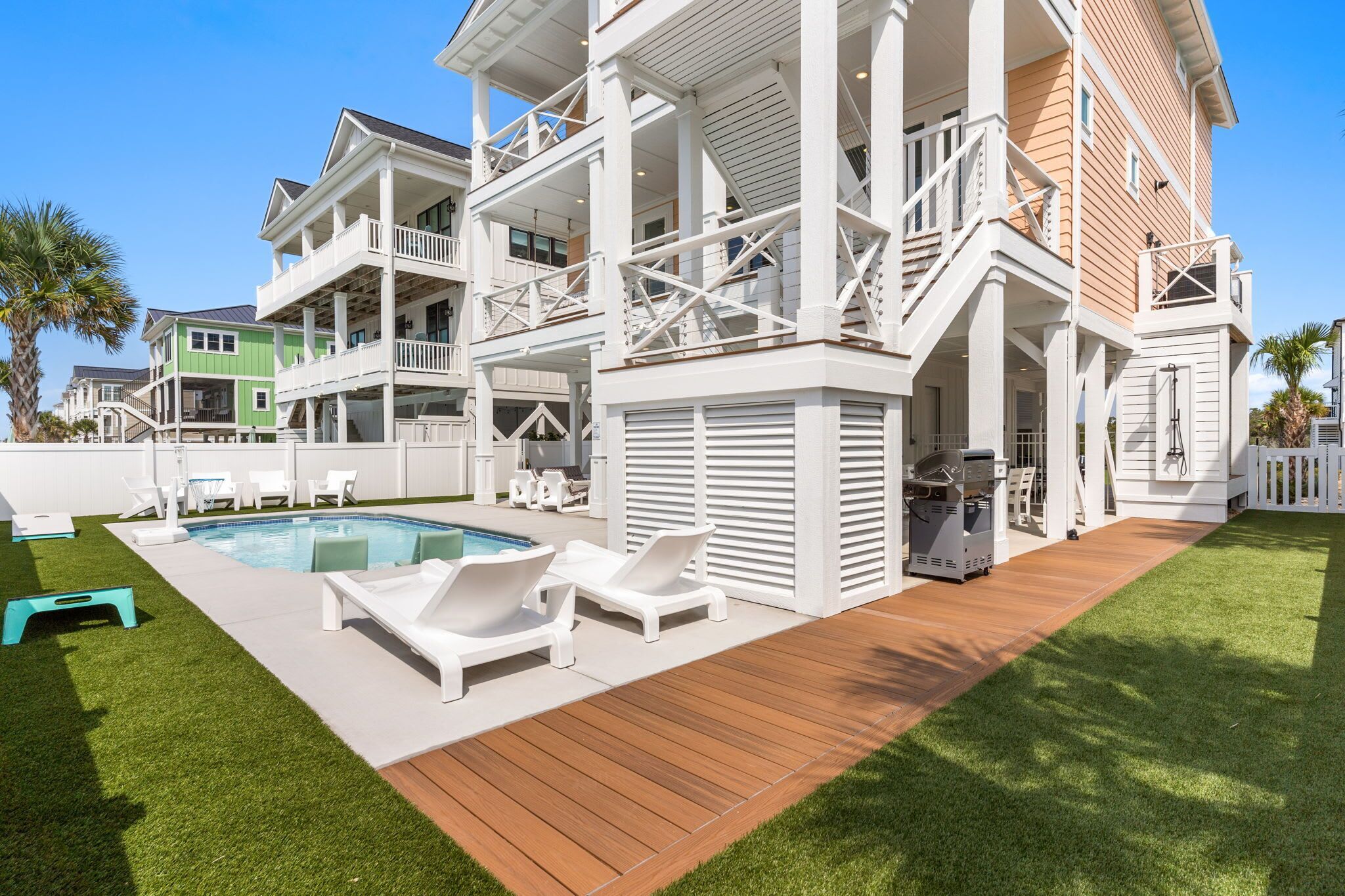 A multi-story house with a pool, outdoor seating, and a covered patio area.