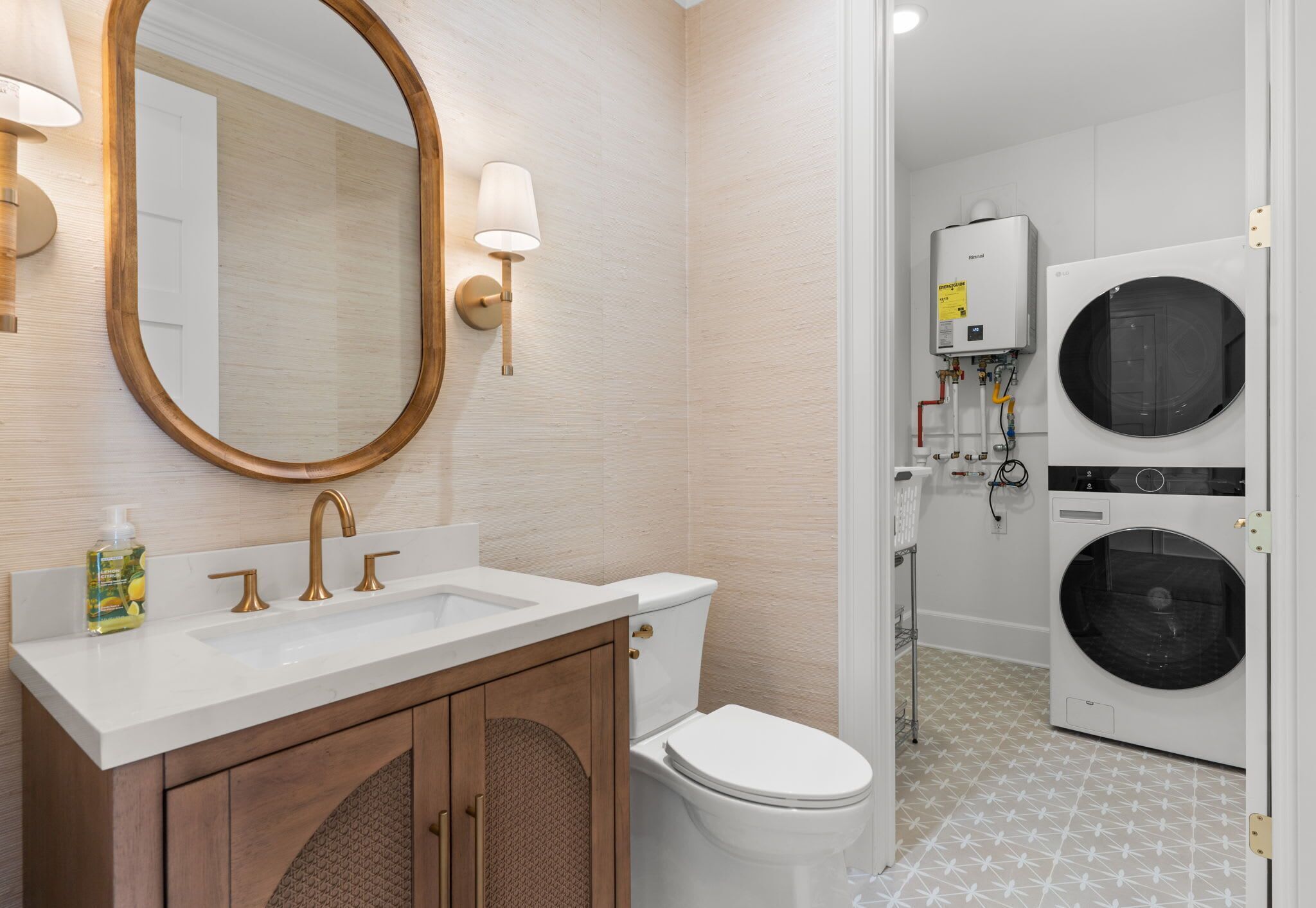 A bathroom with a white sink, gold faucets, a wooden cabinet, a toilet, and a wall-mounted washing machine.