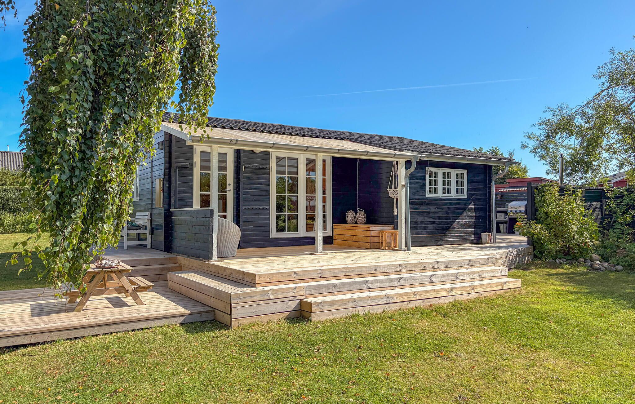 A wooden house with a porch, a small deck, and a garden.