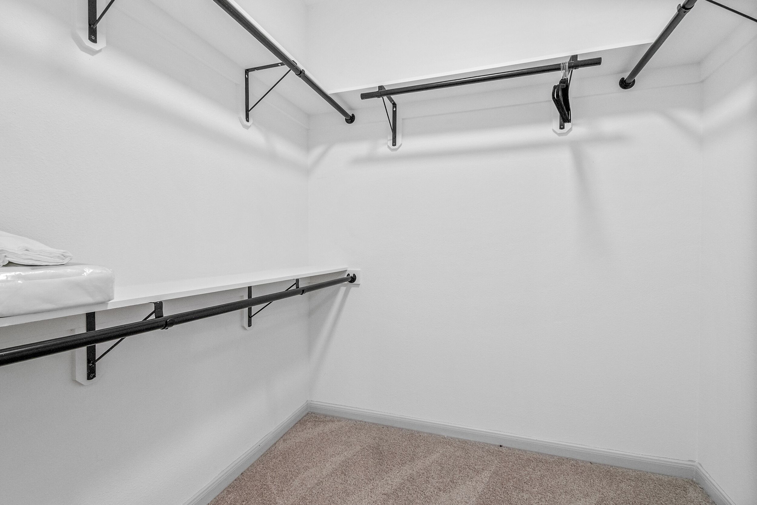 Ein Teil eines Raumes mit weißer Wand, beigeem Teppich und einer weißen Arbeitsplatte mit Handtuch.
