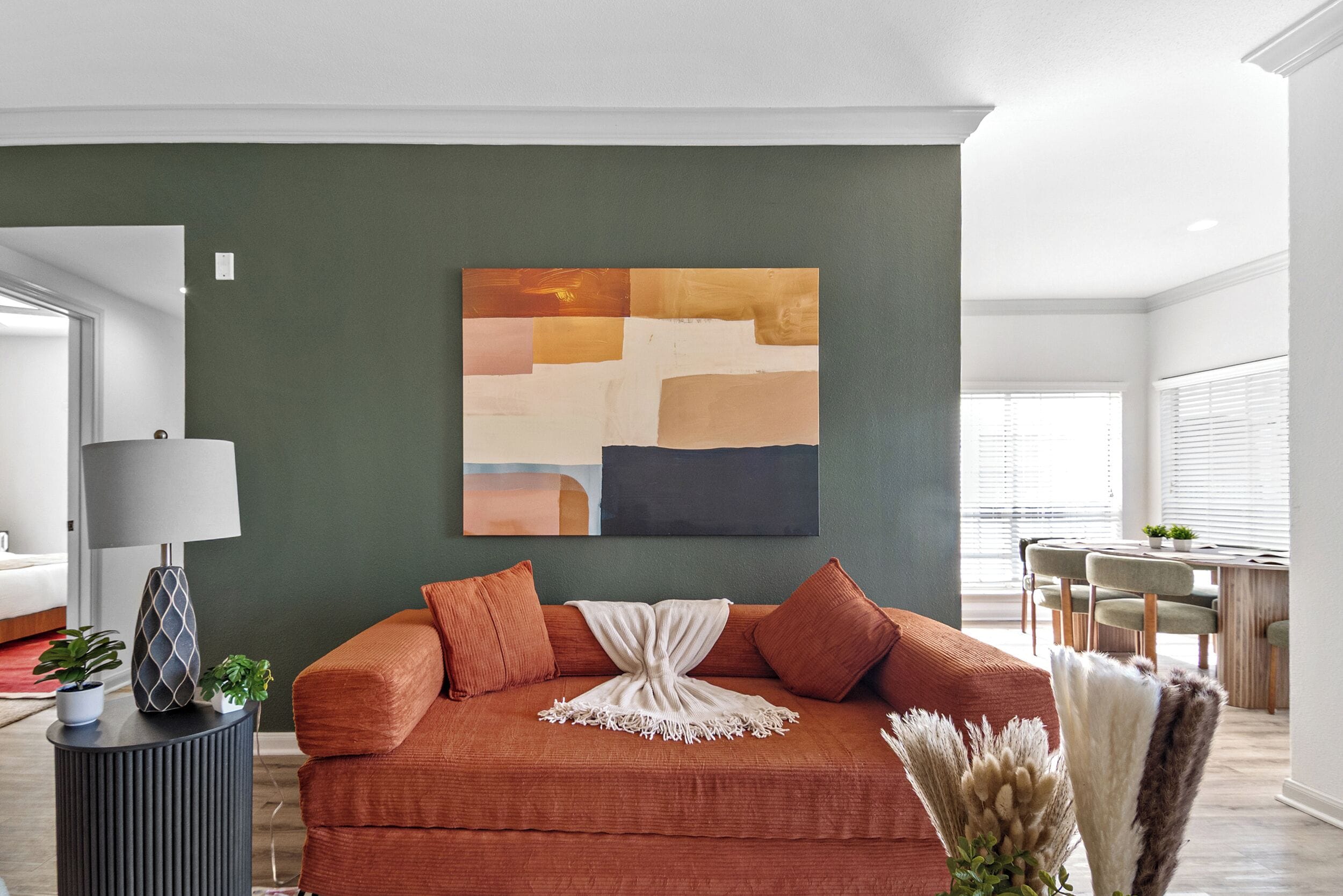 Ein Wohnzimmer mit einer Couch, einem Gemälde und einer Lampe.