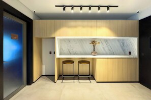 Une cuisine moderne avec un plan de travail en marbre, deux tabourets et un luminaire suspendu au plafond.