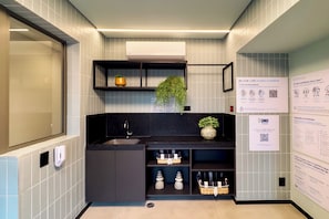 A modern bathroom with a black sink, shelves, and a QR code for a tutorial. - 1003A - Studio apartment with rooftop pool, 5 minutes from CGH airport. (São Paulo)