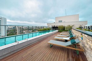 A rooftop pool area with lounge chairs and a view of the cityscape. - 1003A - Studio apartment with rooftop pool, 5 minutes from CGH airport. (São Paulo)