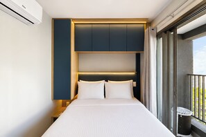 A hotel room with a bed, a headboard, and a window with a view. - 1003A - Studio apartment with rooftop pool, 5 minutes from CGH airport. (São Paulo)